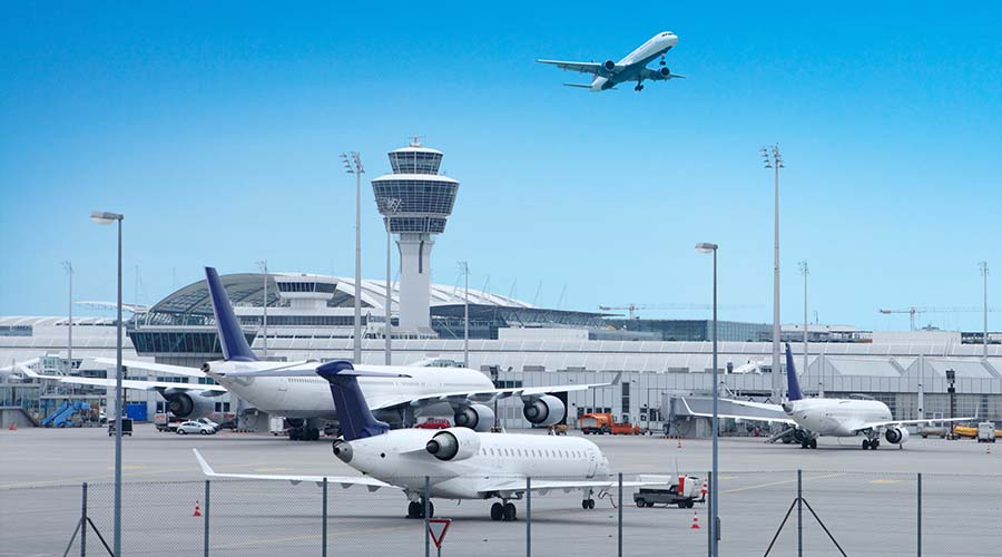airport with planes on the ground and a plane in flight