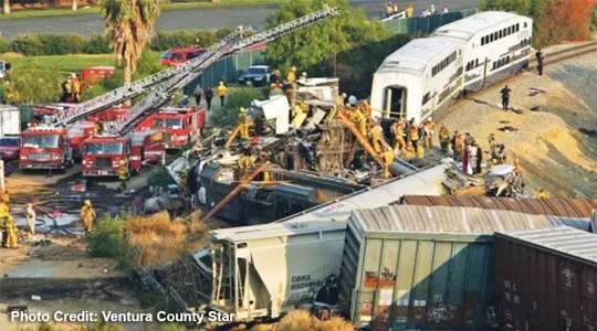 Derailed train surrounded by fire trucks and rescue workers.